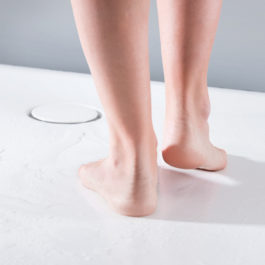 les pieds nus d'une femme sur le receveur de douche blanc Setaplano de geberit