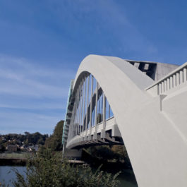 Un pont en béton de forme courbe enjambre une belle rivière