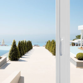 Une baie vitrée Prefal s'ouvre sur une magnifique terrasse ensoleillée. Au moin la mer bleue pour horizon.