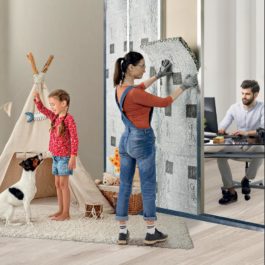 une jeune femme pose un isolant mural dans un HLM