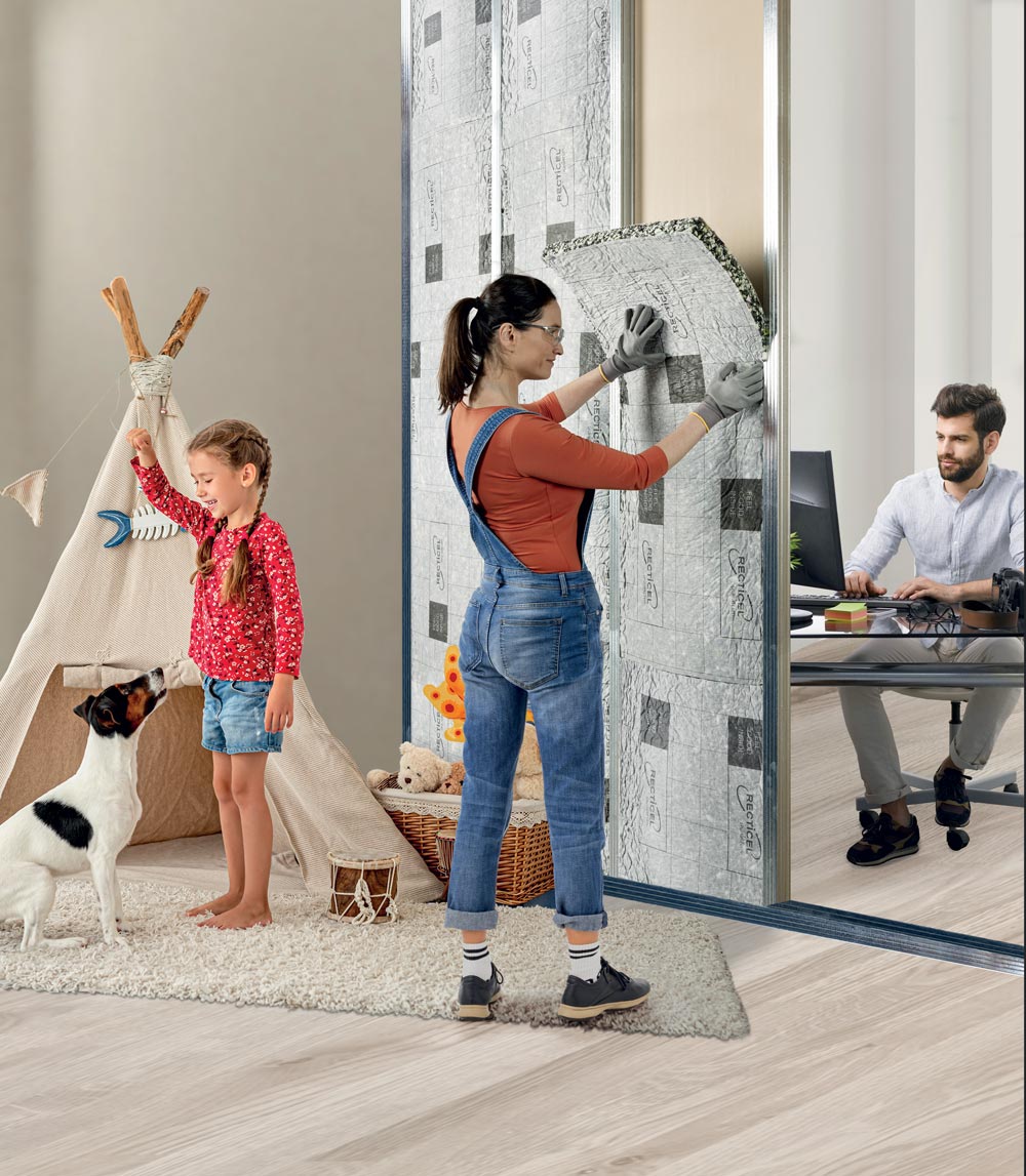 une jeune femme pose un isolant mural dans un HLM